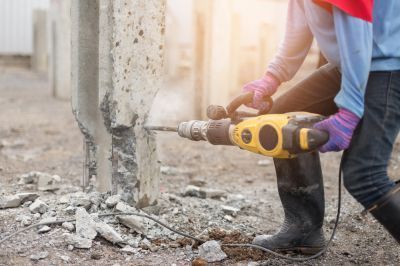 A man is pouring concrete into a wooden frame.