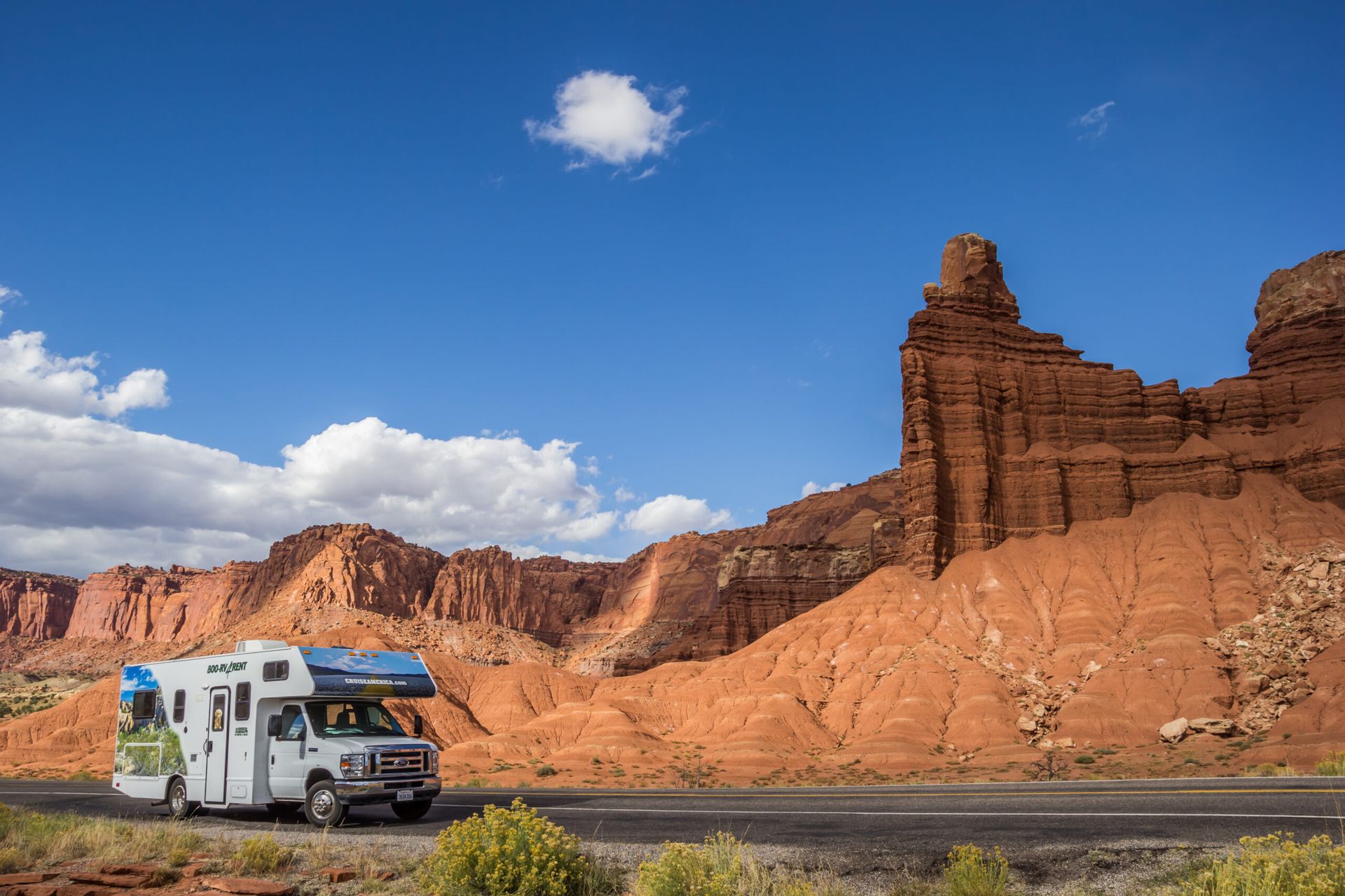 A rv is driving down a road in the desert.