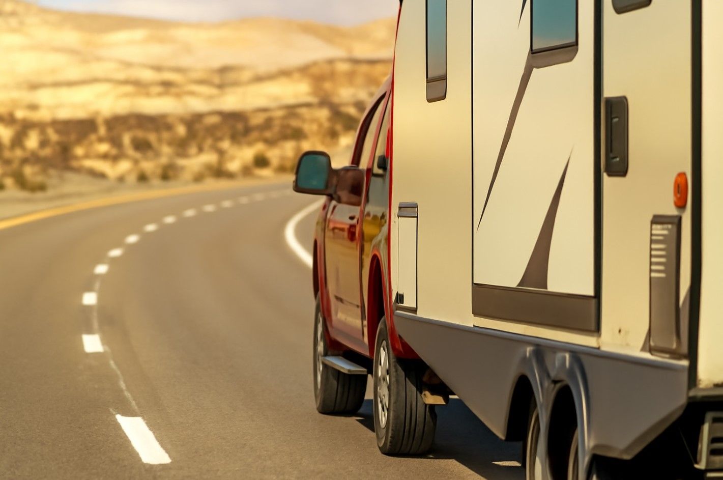 A truck is towing a trailer down a road.