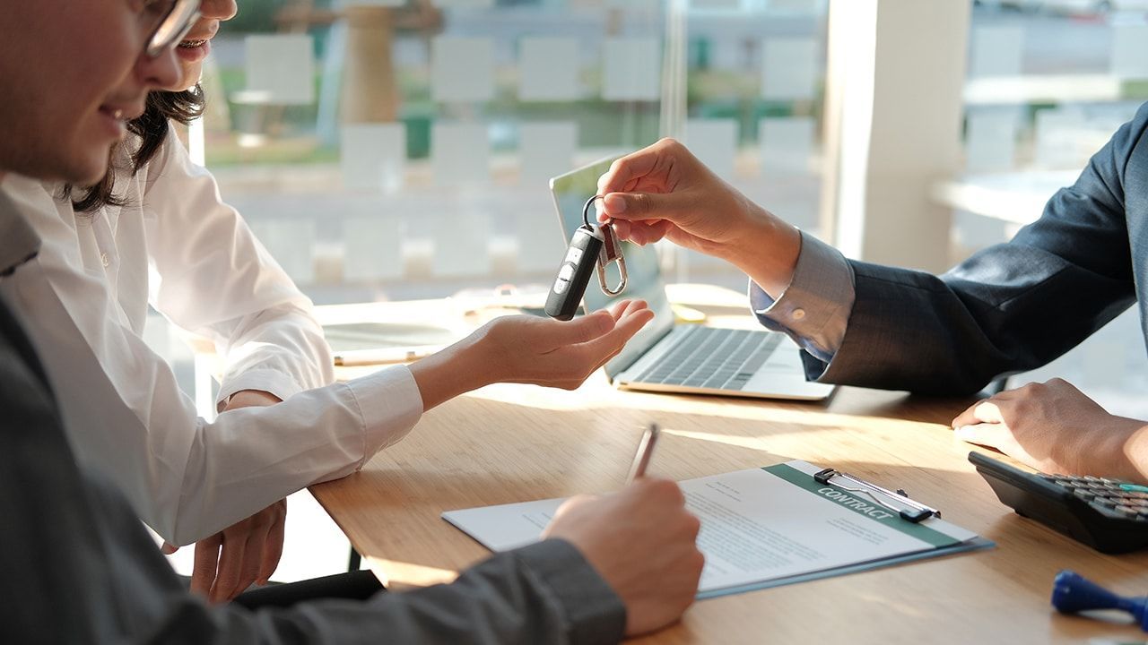 A man is giving a car key to a woman.