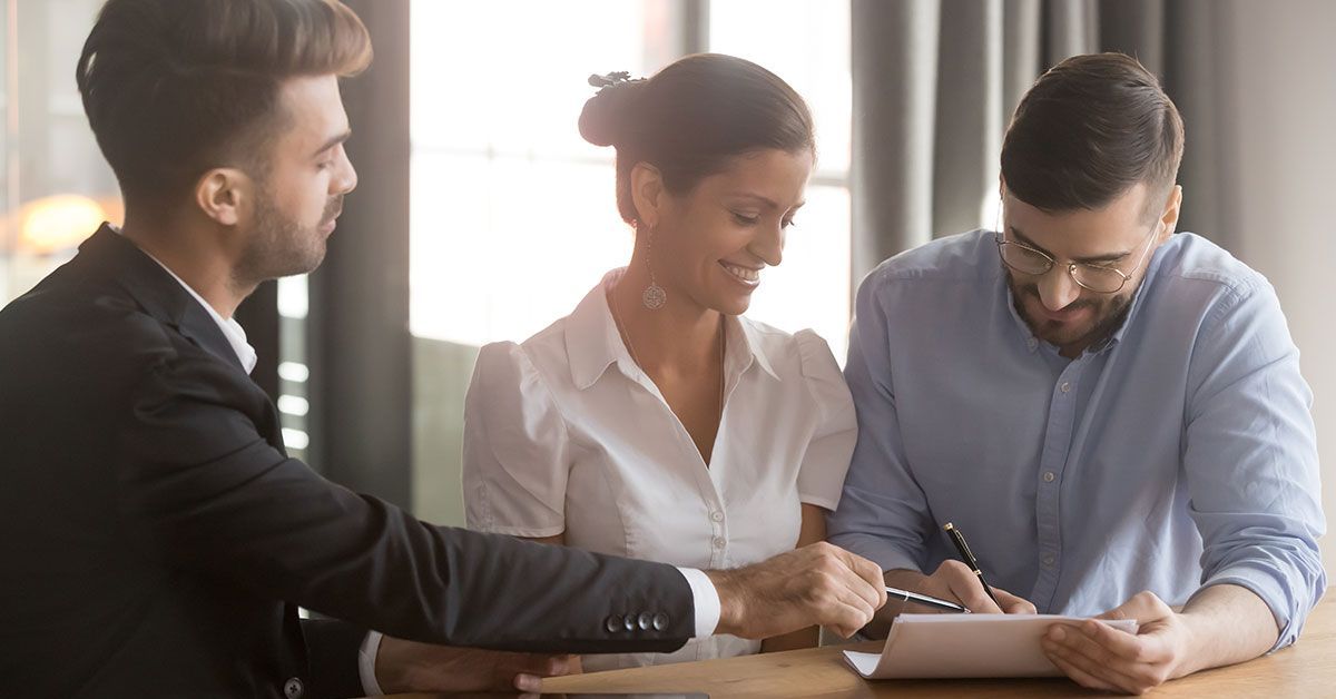 A man and a woman are sitting at a table signing a document.