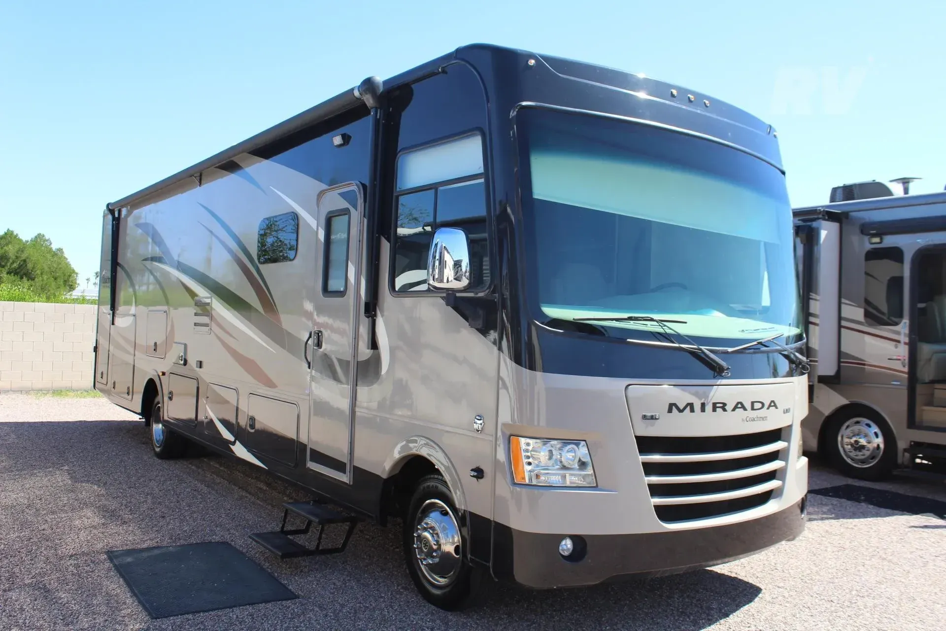 Tan and black Mirada RV parked outside on a sunny day.