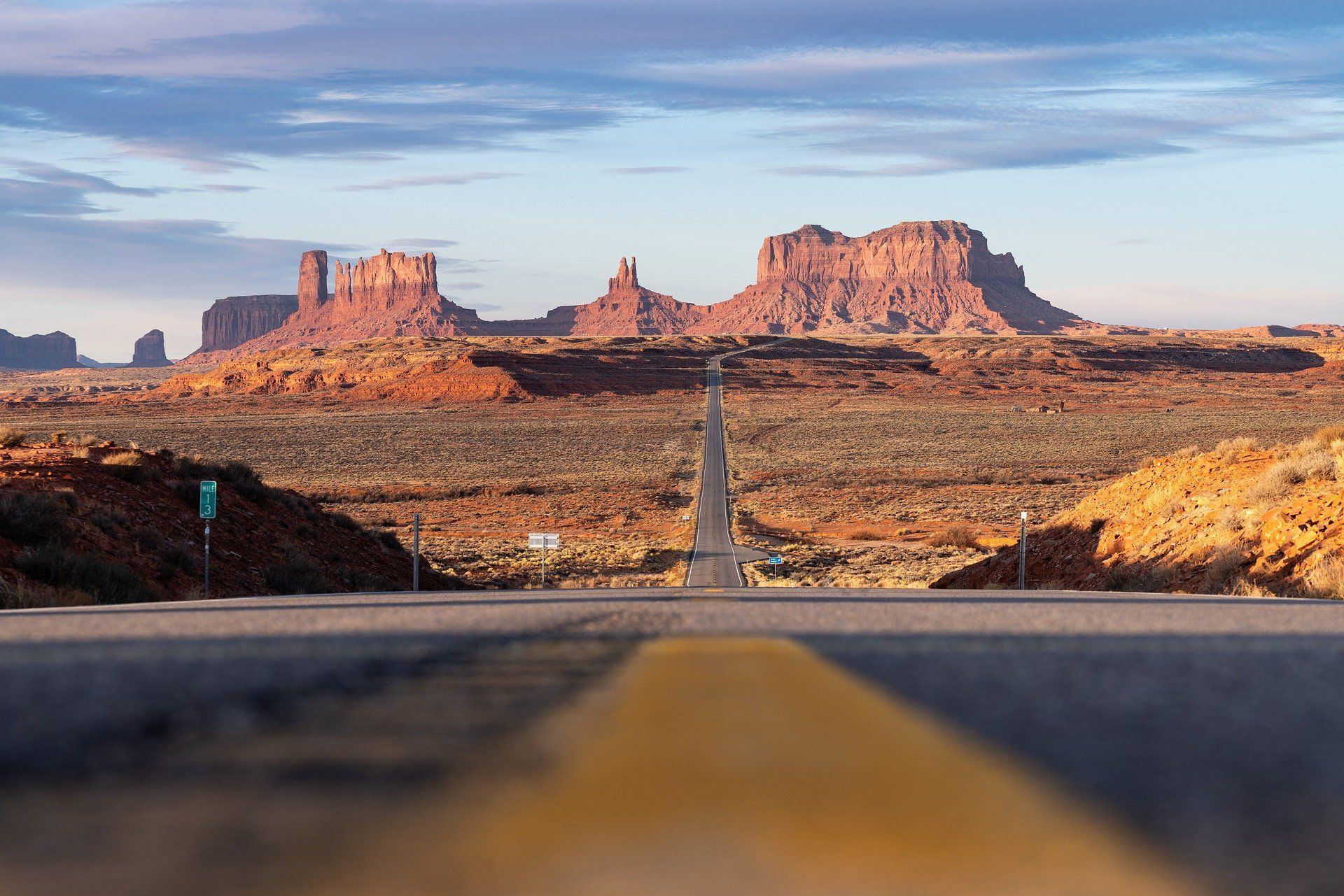 A road going through a desert with mountains in the background.