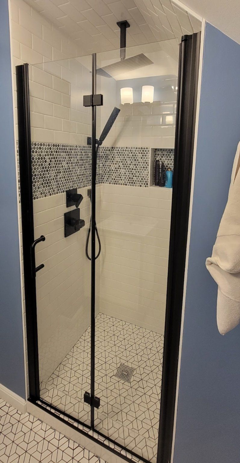 Modern shower with black frame and fixtures, white and mosaic tile.