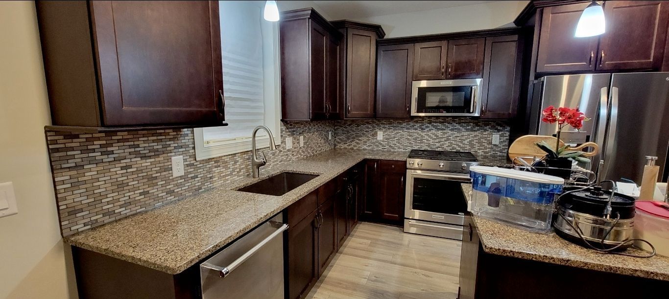 A kitchen with dark wood cabinets, granite countertops, and stainless steel appliances.
