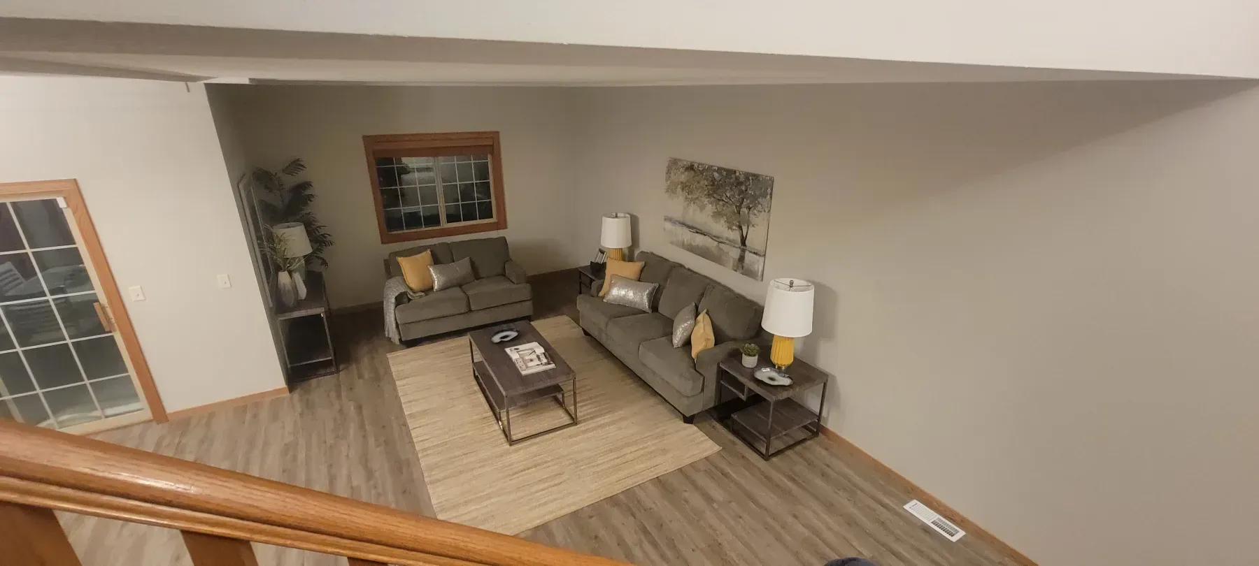 Living room with two gray sofas, beige rug, coffee table, and artwork.