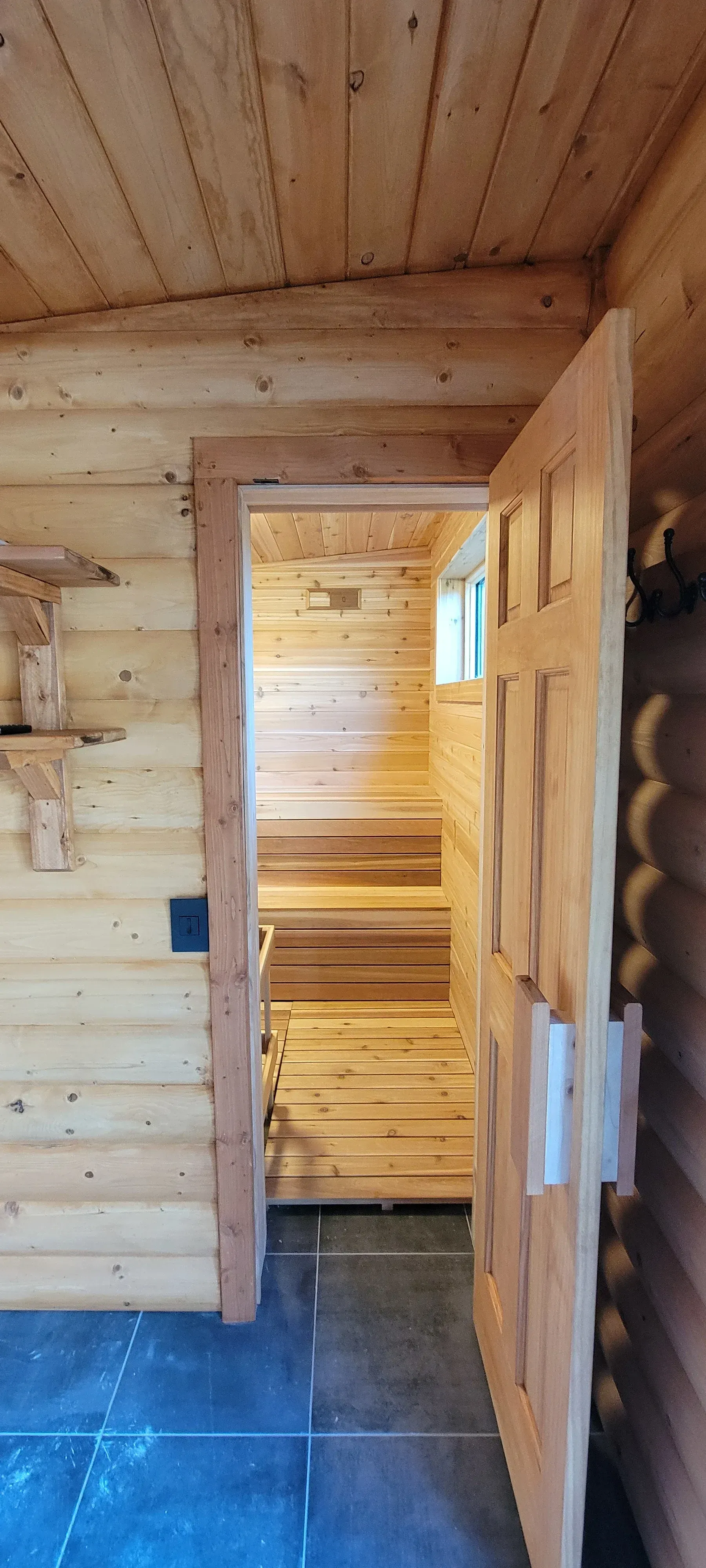 Open wooden door reveals an interior wooden sauna.