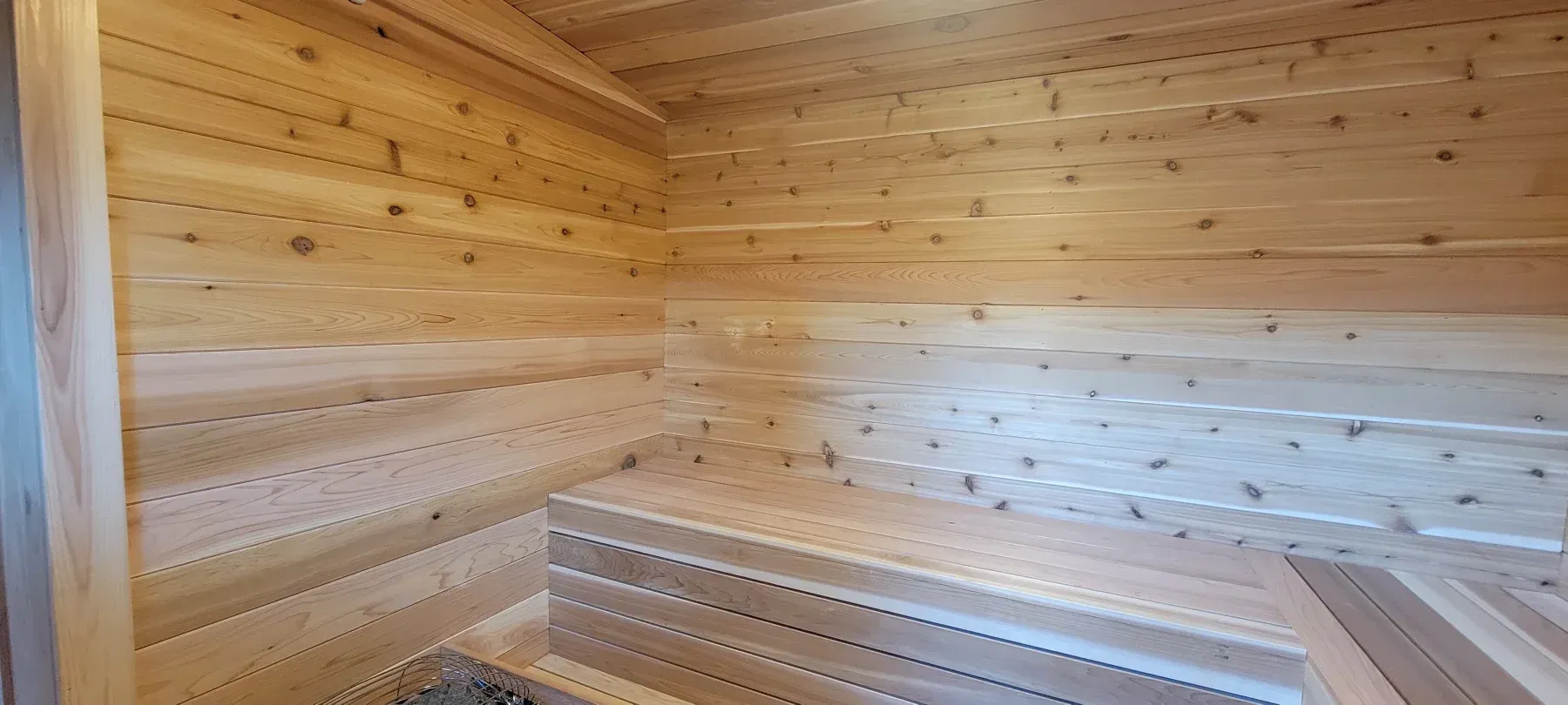 Wooden sauna interior with slatted walls, ceiling, and benches.