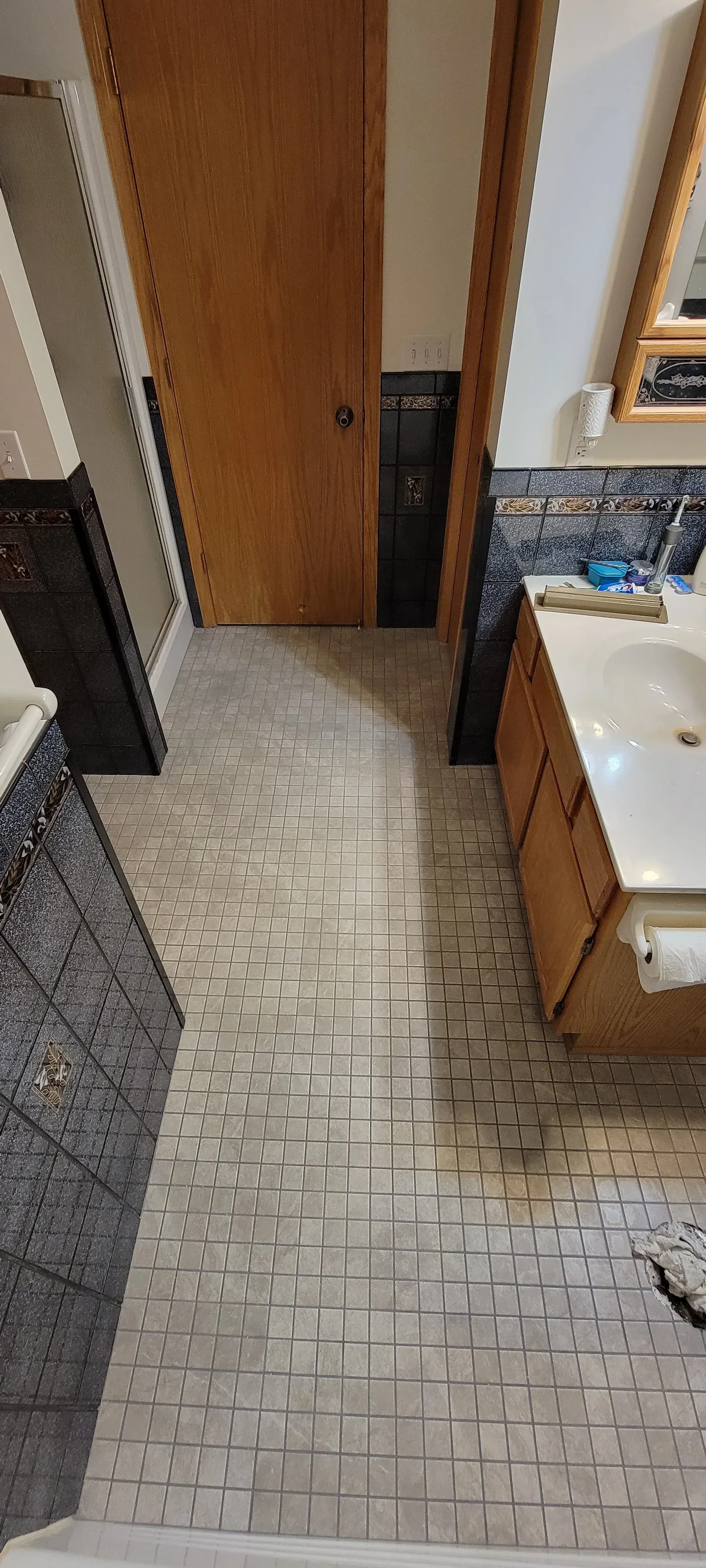 Bathroom with tile floor, wooden door and vanity.