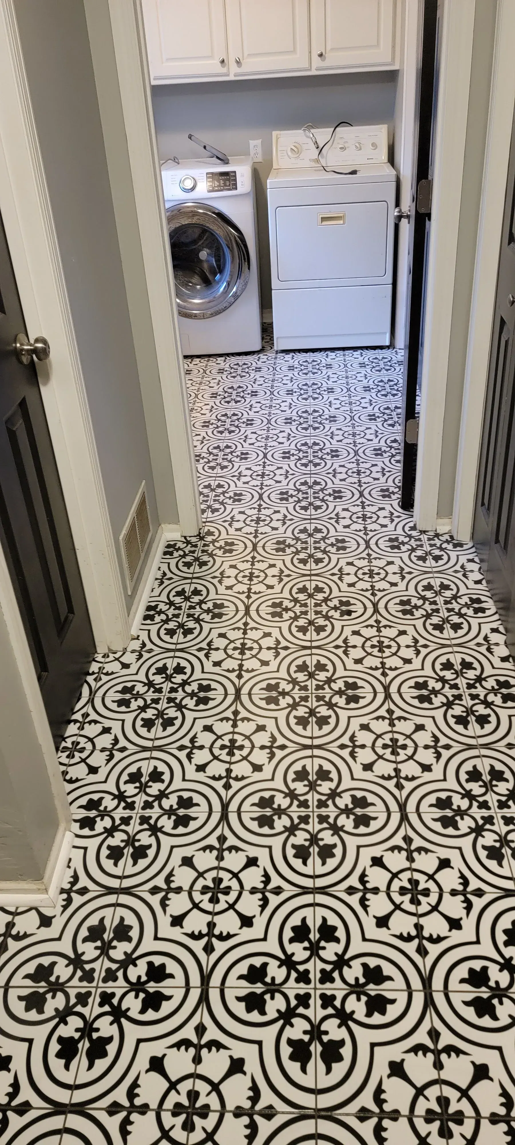 Laundry room with black and white patterned tile flooring. A washing machine and dryer are visible.