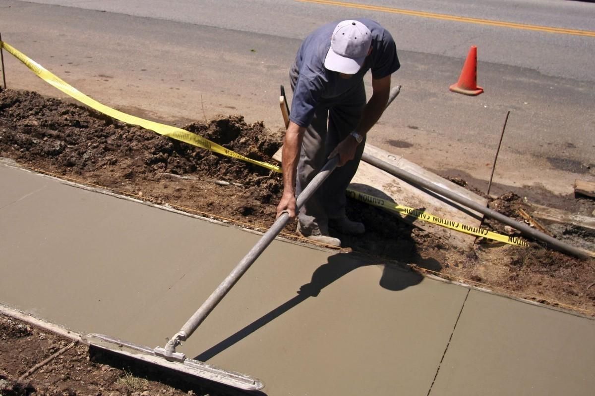 A man is working on a sidewalk with a broom