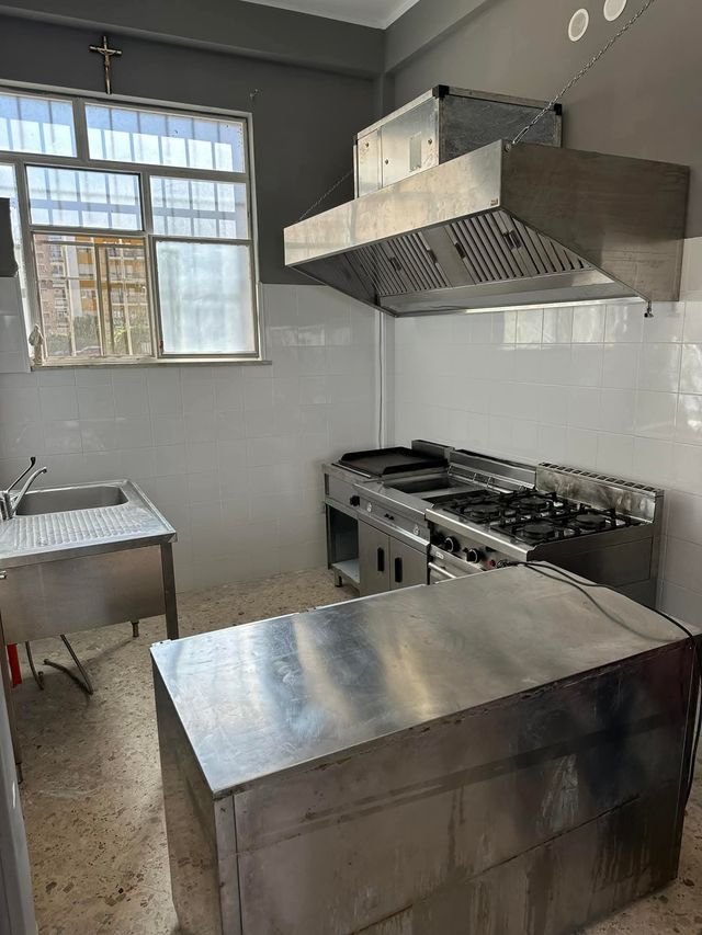 Cucina commerciale con elettrodomestici in acciaio inossidabile e finestra.