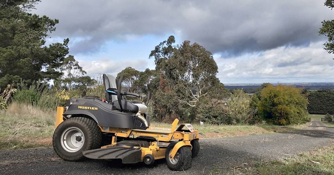 A Yellow And Black Lawn Mower Is Parked On A Gravel Road In A Field — Leslie Farm & Garden Machinery In South Grafton, NSW