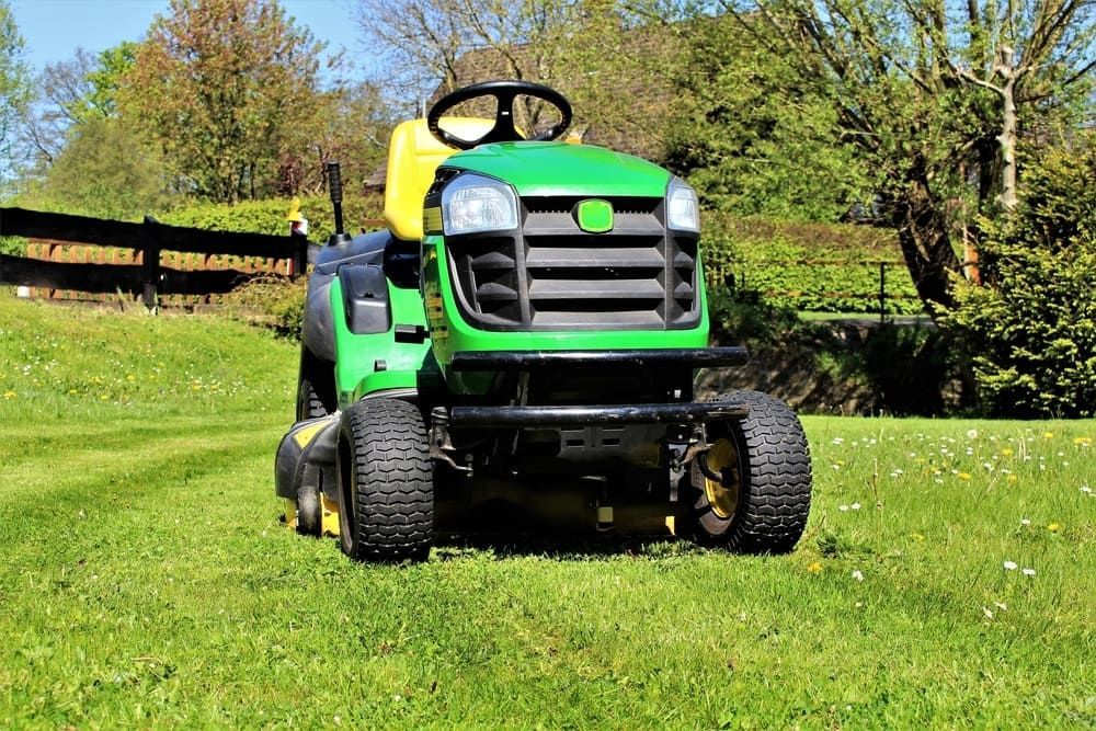  A green tractor  sat unattended on a grassy field.