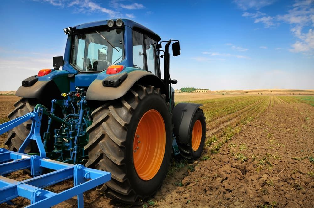 A Tractor Is Plowing A Field With A Plow Attached To It — Leslie Farm & Garden Machinery In South Grafton, NSW