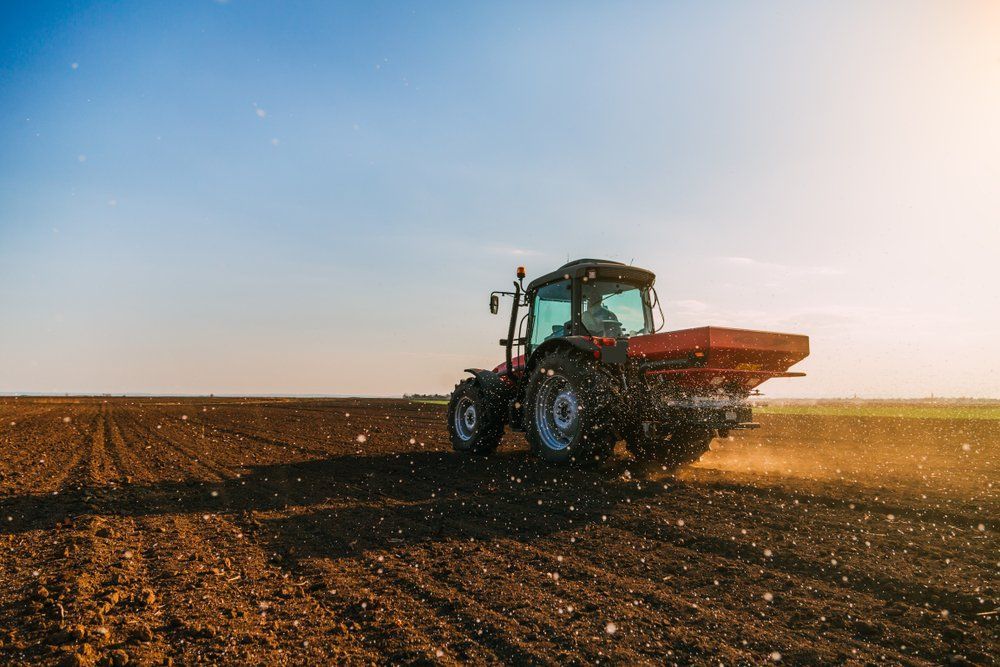 A Tractor Is Plowing A Field At Sunset — Leslie Farm & Garden Machinery In South Grafton, NSW