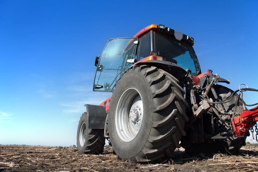 A Tractor Is Plowing A Field With A Plow Attached To It — Leslie Farm & Garden Machinery In South Grafton, NSW
