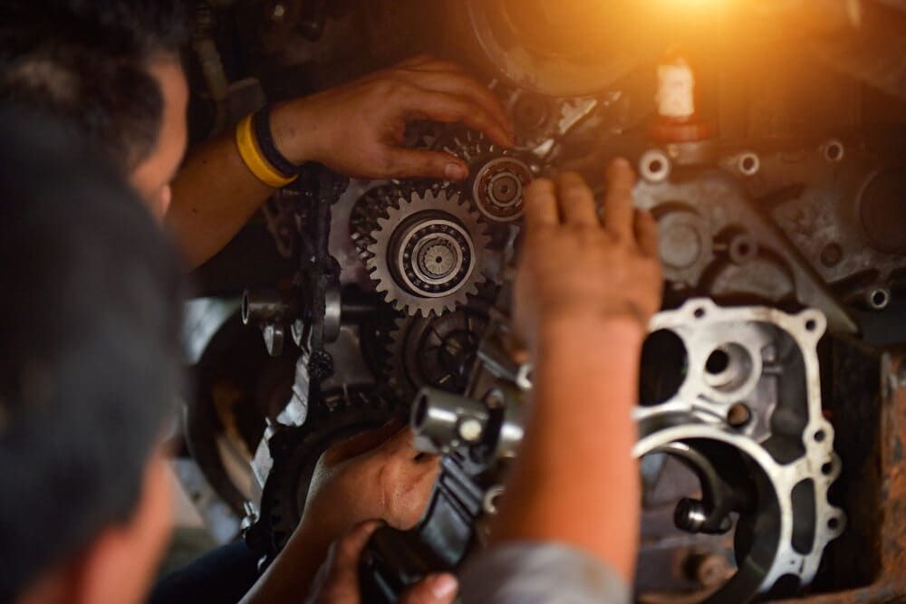 Two Men Are Working On A Farm Tractor Engine — Leslie Farm & Garden Machinery In South Grafton, NSW