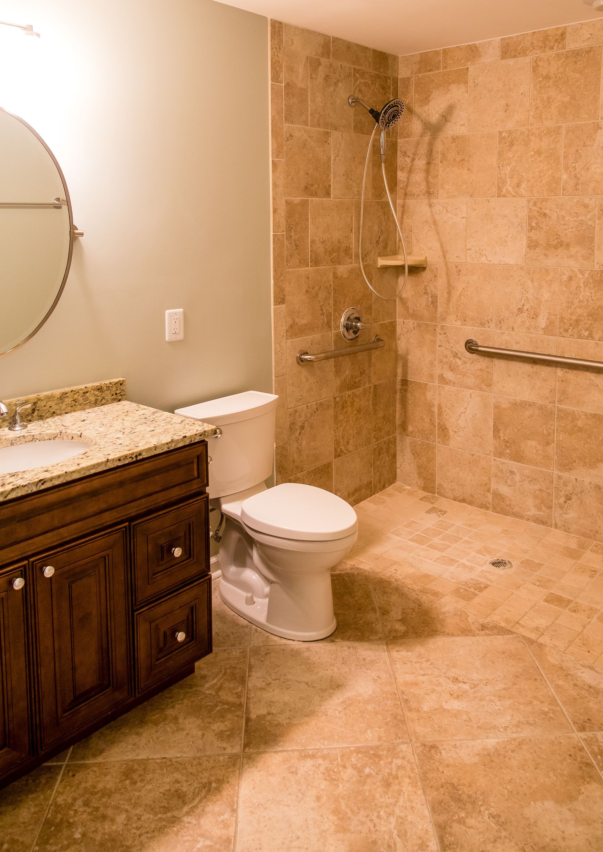 A bathroom with a toilet, sink  mirror and walk in shower.