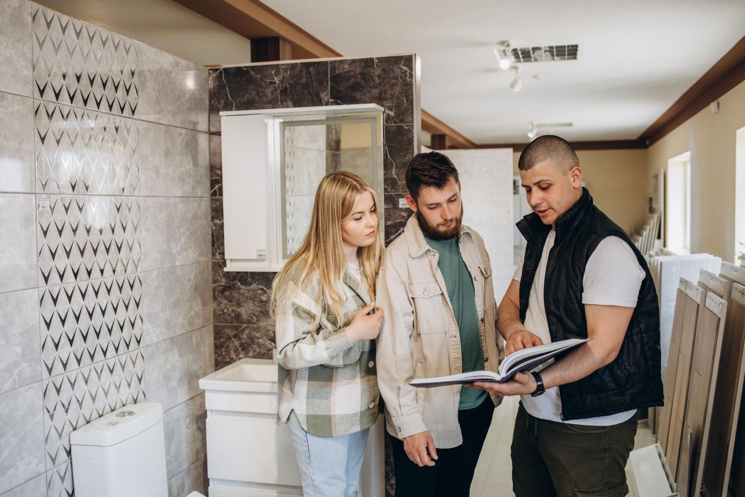A couple and a salesperson looking at a brochure in a bathroom showroom.