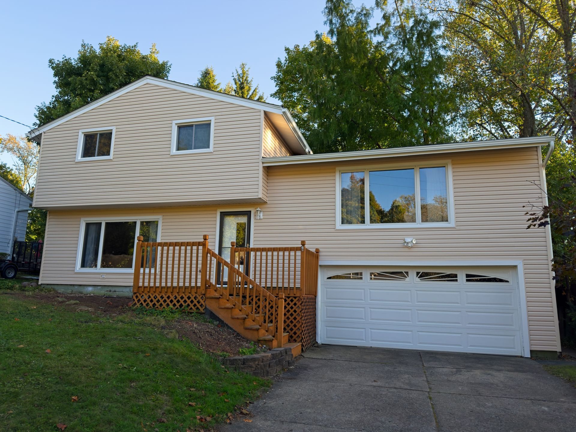 Two-story house with beige siding, a wooden deck, and a white garage door.