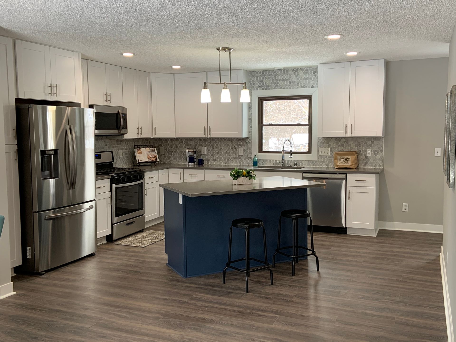 A kitchen with stainless steel appliances and a blue island.