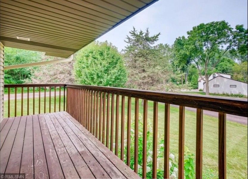 An empty deck with a wooden railing and trees in the background