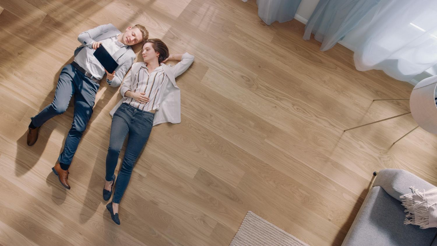 A man and a woman are laying on the floor in a living room.