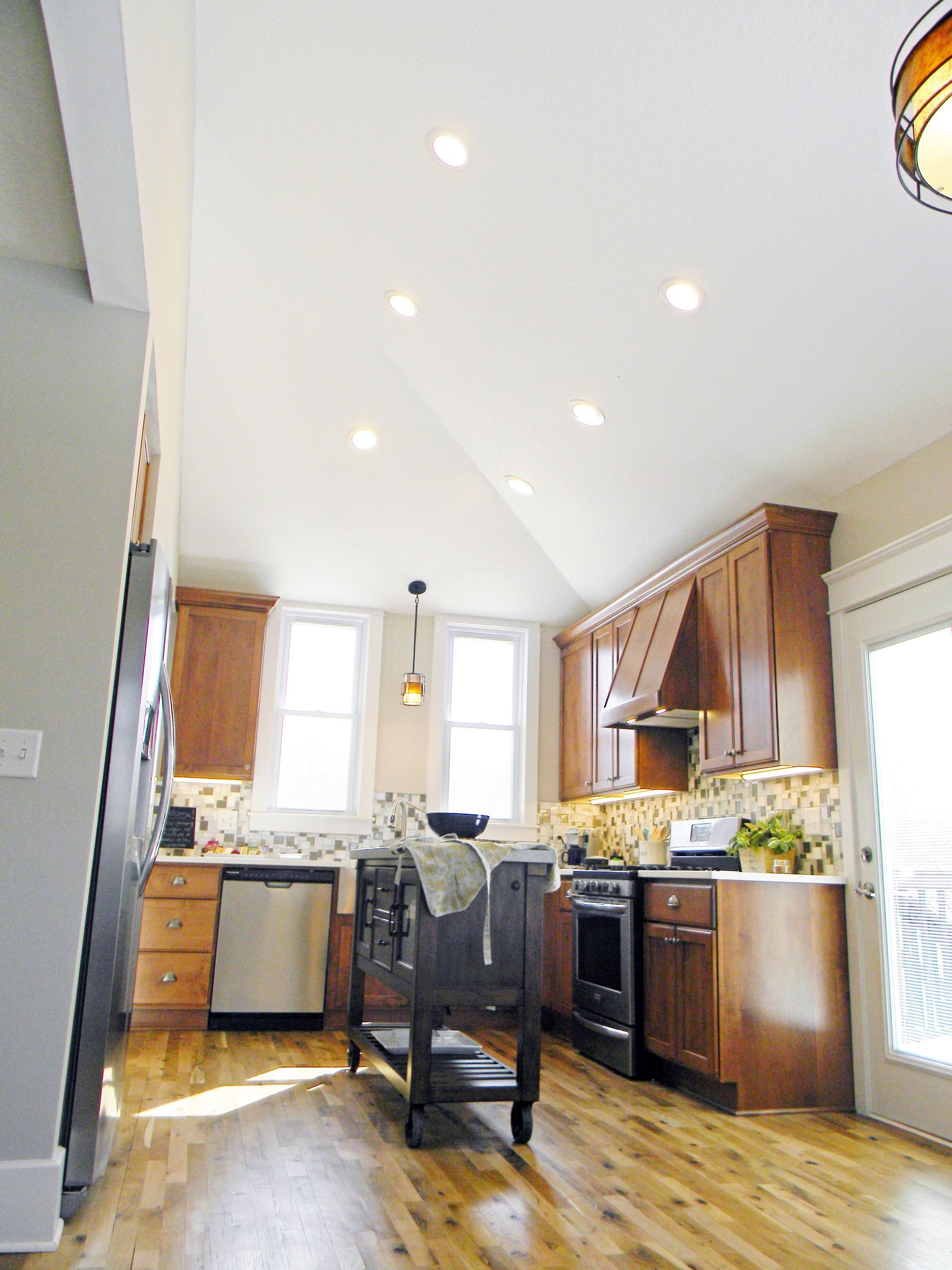 Kitchen with wood cabinets, island, and high, angled ceiling. Natural light and recessed lighting.