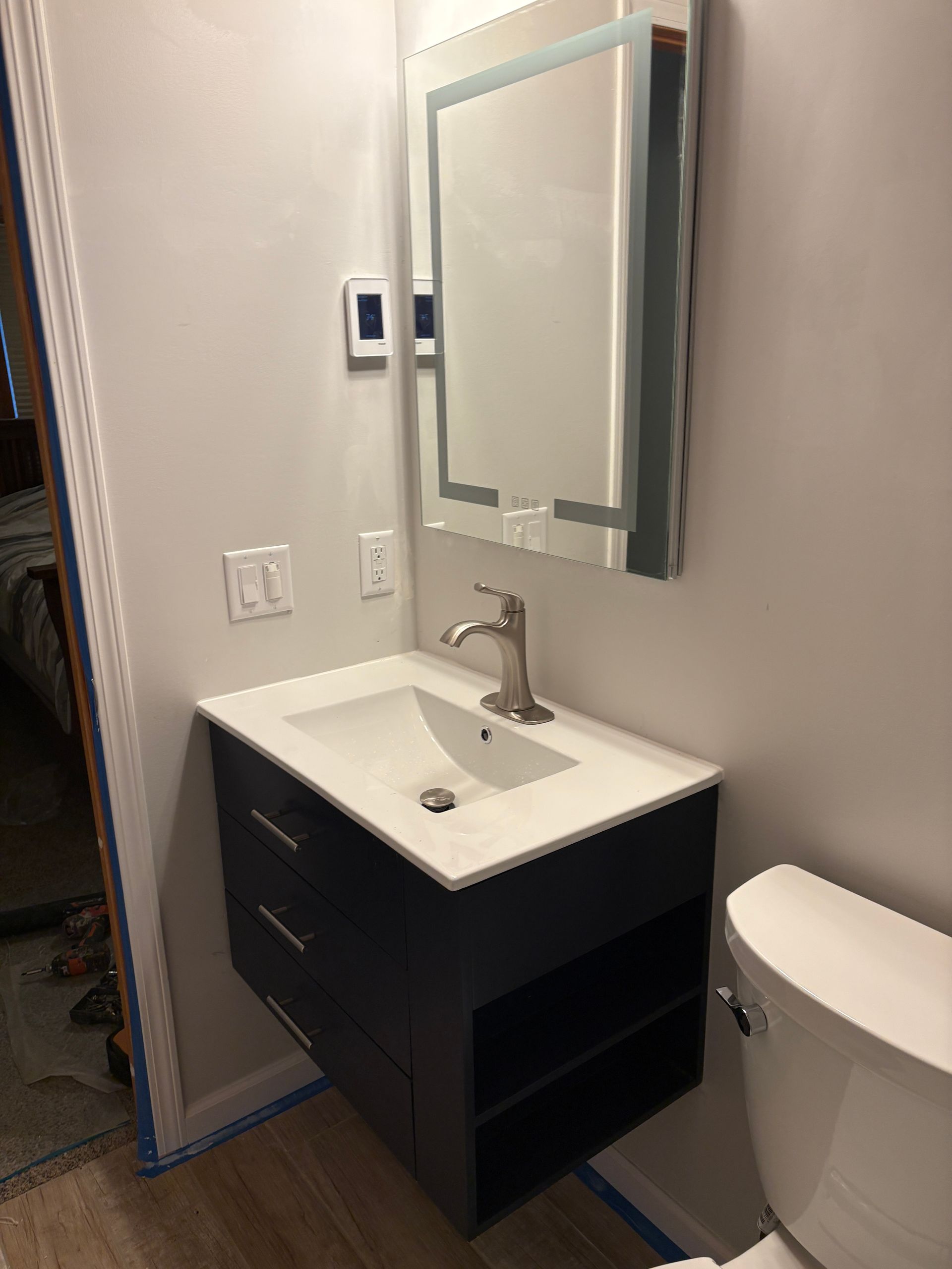Bathroom with floating vanity, sink, LED mirror, and toilet.