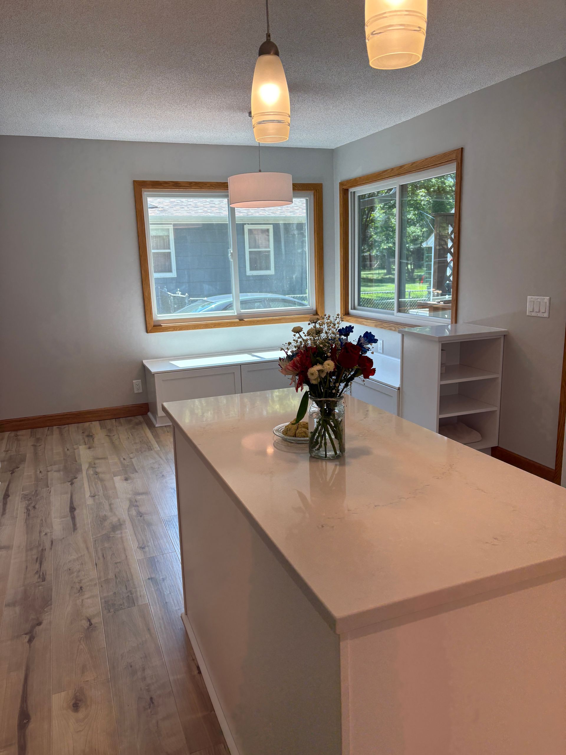 Kitchen with white island, flowers, wood trim, and two windows.