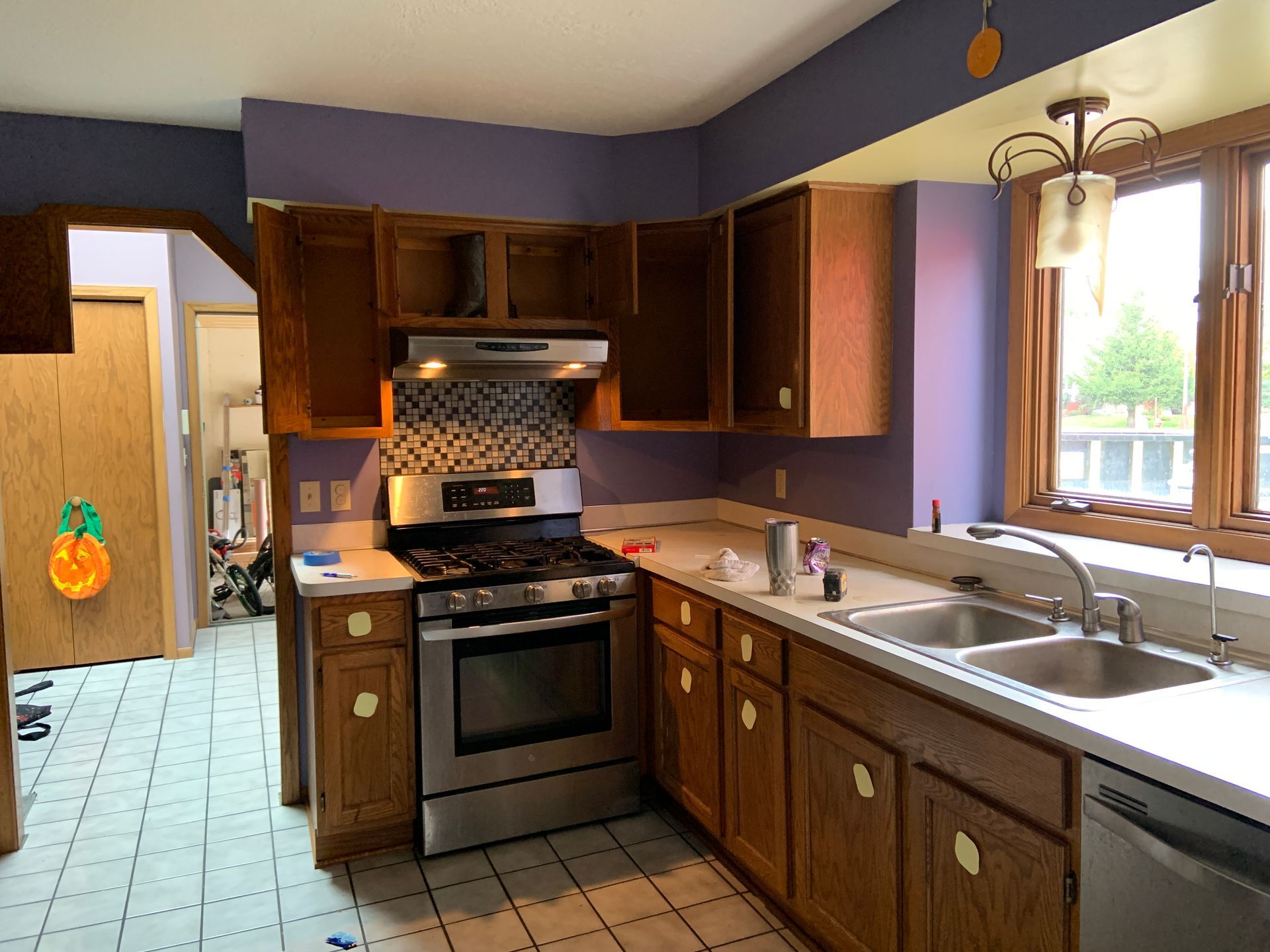 Kitchen with oak cabinets, stainless steel appliances, and purple walls being renovated.