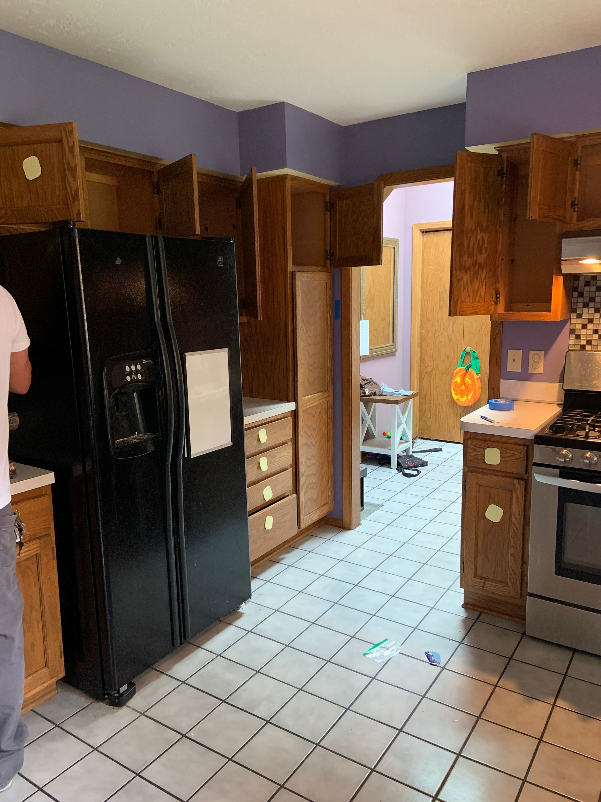 Kitchen with dark refrigerator, wood cabinets, and purple walls; undergoing renovation.