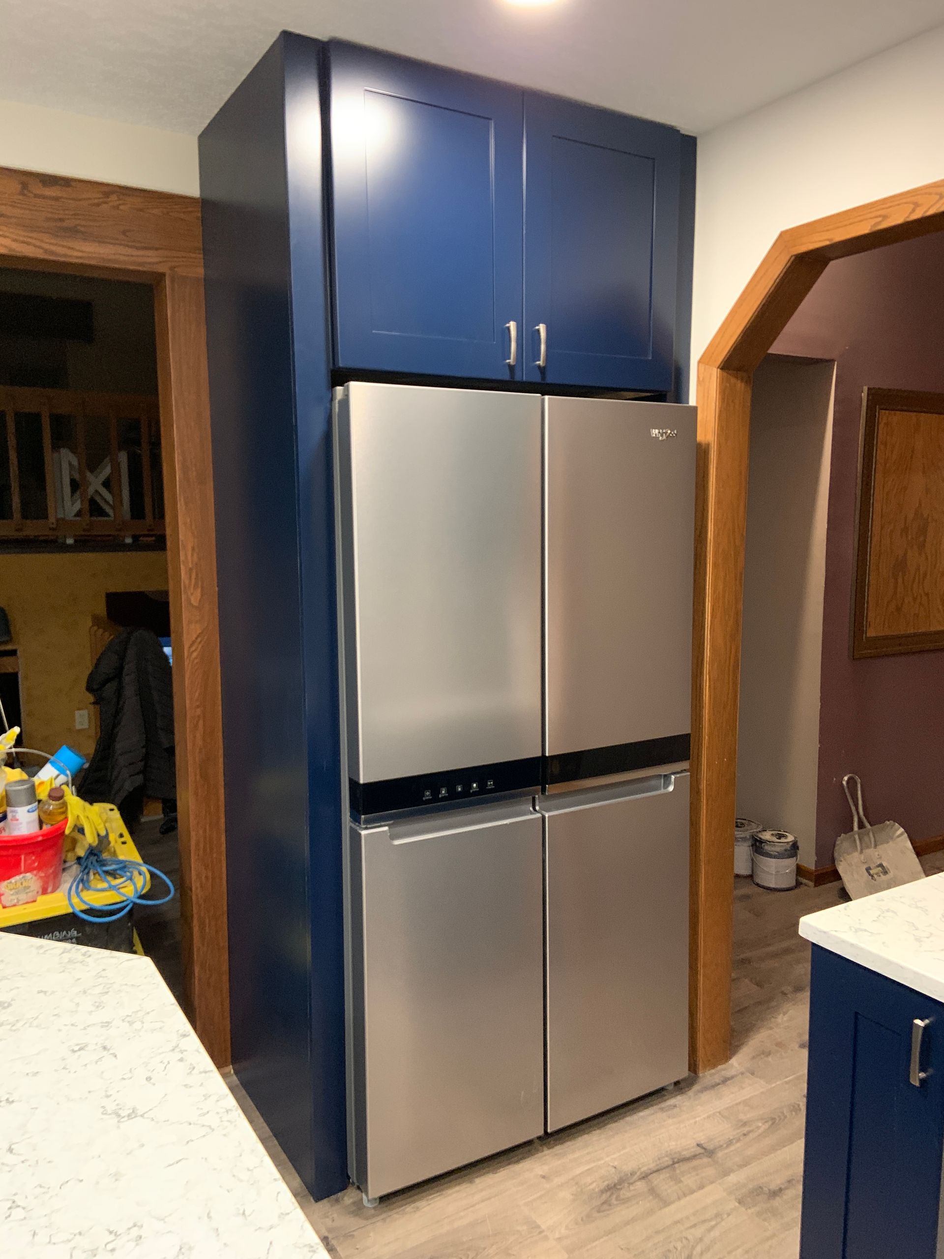 Blue cabinets surround a stainless steel refrigerator. Kitchen remodel in progress.