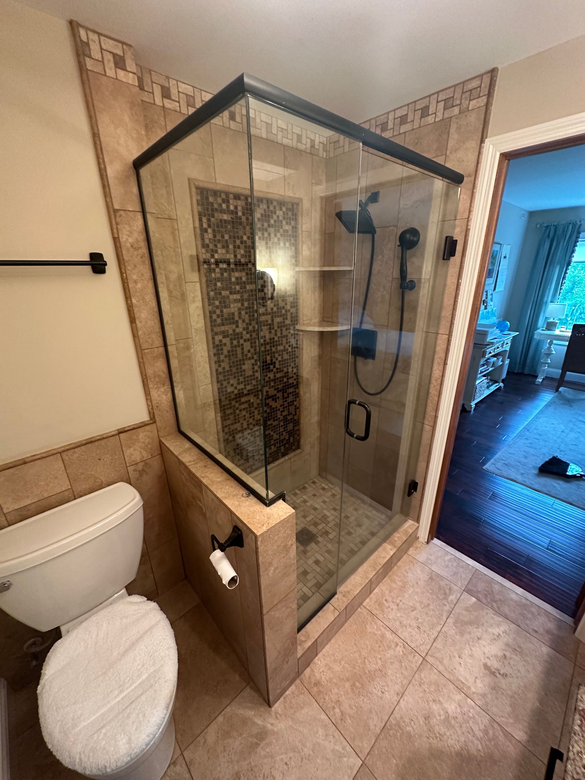 Bathroom with a glass shower enclosure and tiled walls. A toilet is visible in the foreground.