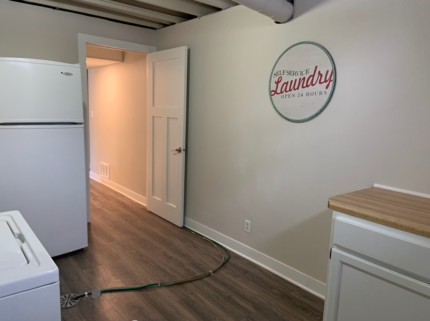 Laundry room with white appliances, wooden cabinets, a door, and a 