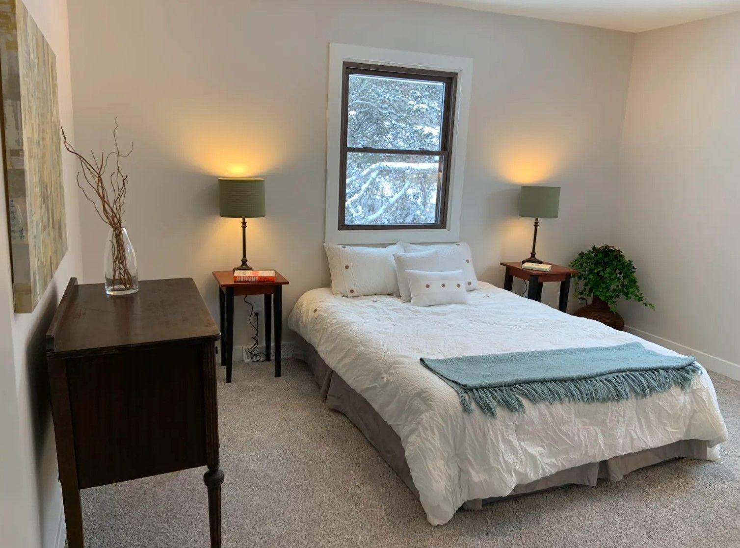 Bedroom with bed, nightstands, lamps, window, and small decorative plant.