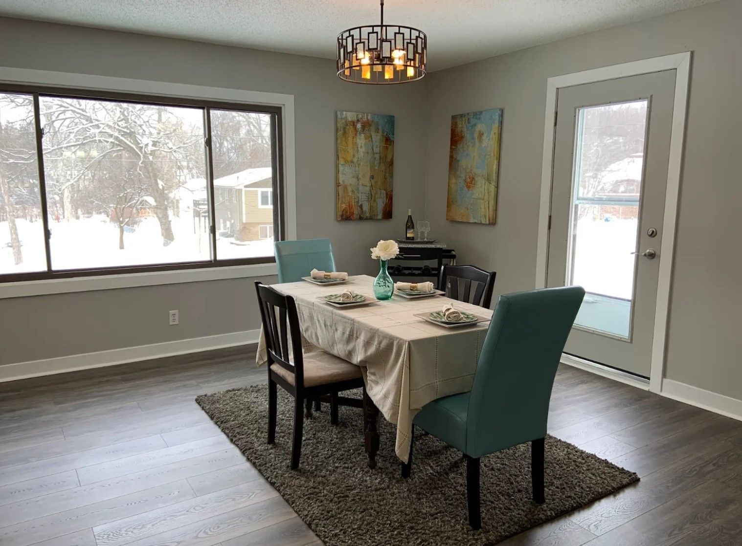 Dining room with table, chairs, art, and a snowy window view.