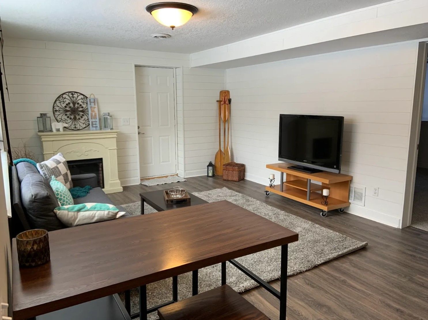 Living room with shiplap walls, fireplace, TV, and a dining table.