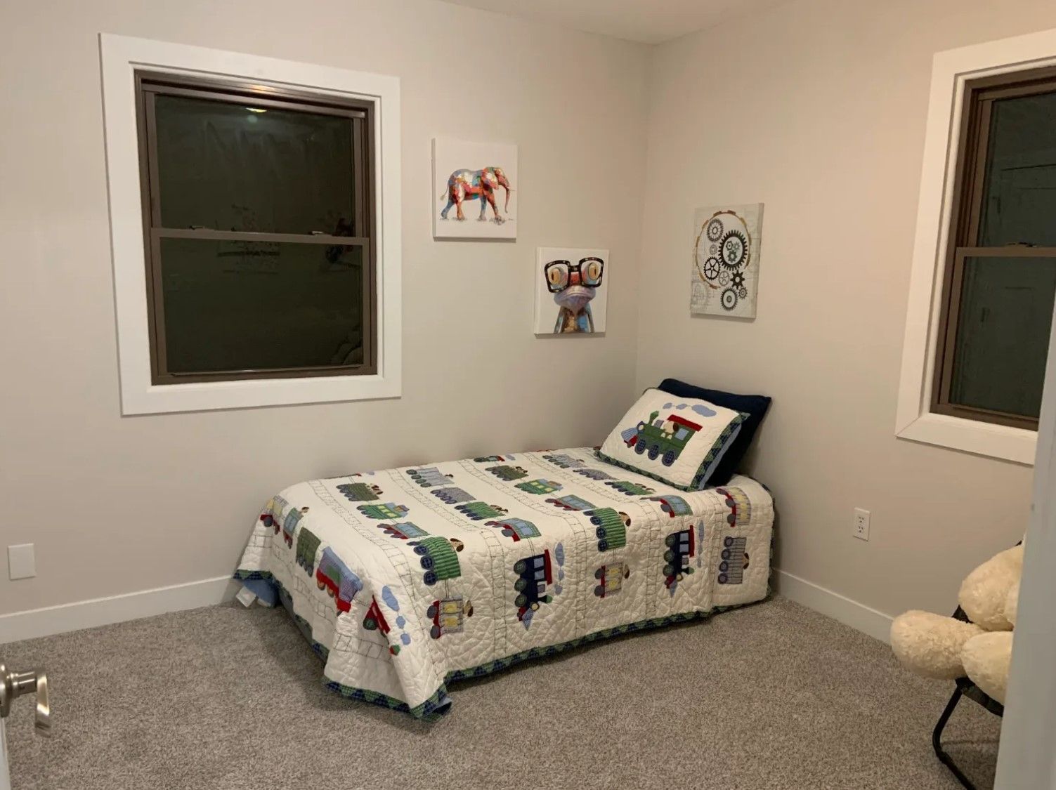 A small child's bedroom with a twin bed, art on the wall, and a stuffed animal.