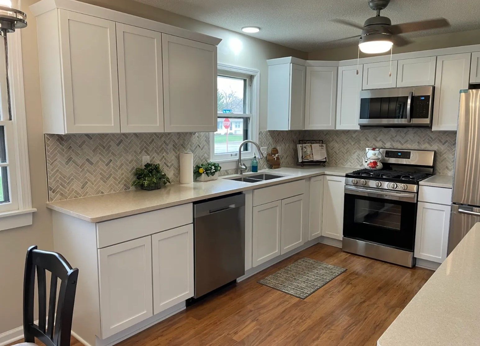 White kitchen with stainless steel appliances, white cabinets, and light-colored countertops.