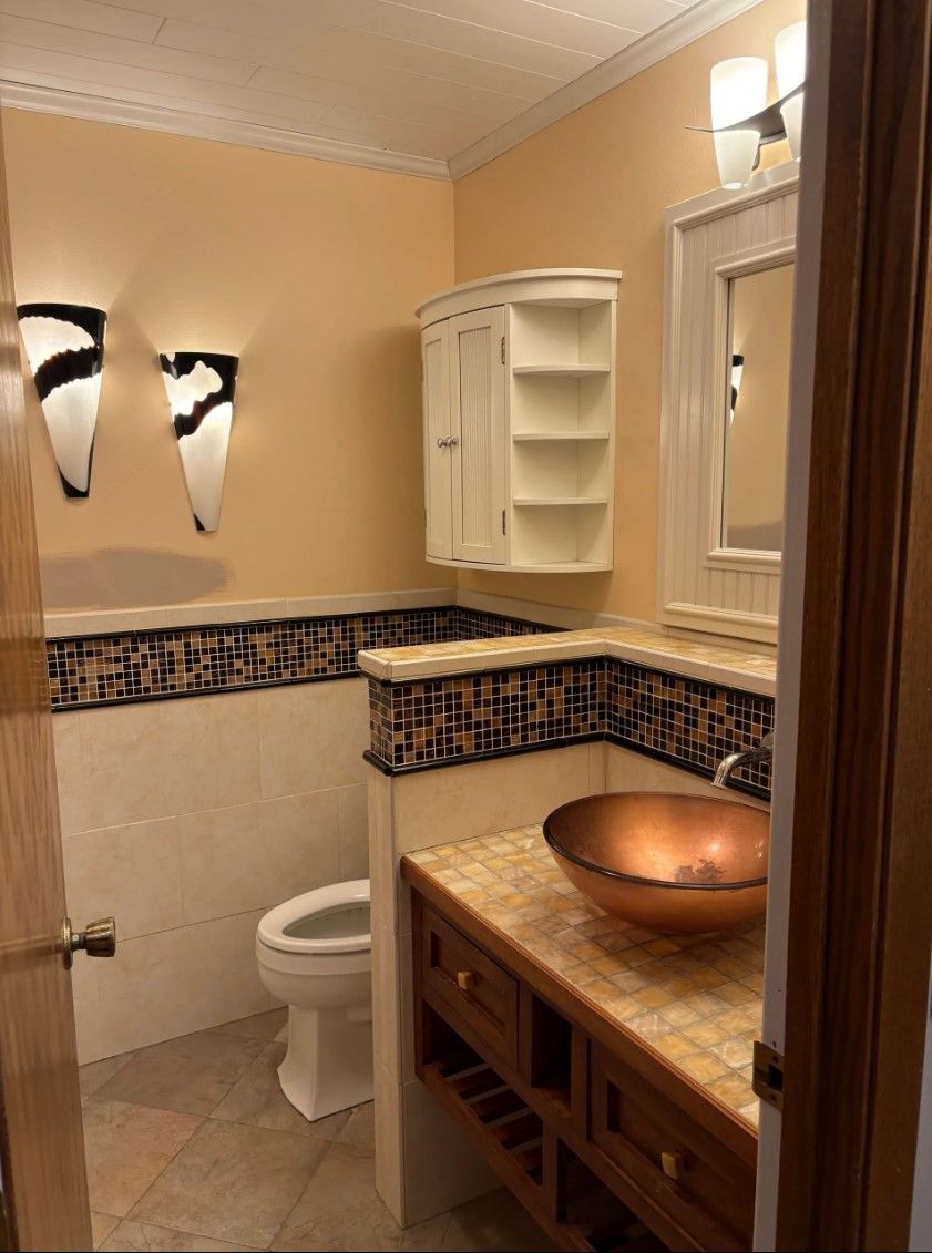 Bathroom with peach walls, white trim, copper sink, mosaic tile, and white toilet.
