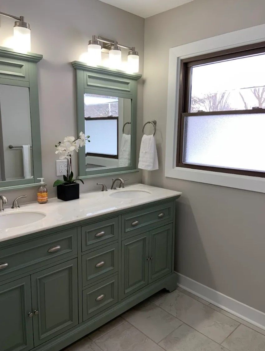 Bathroom with mint green vanity, double sinks, marble countertop, silver fixtures, and frosted window.