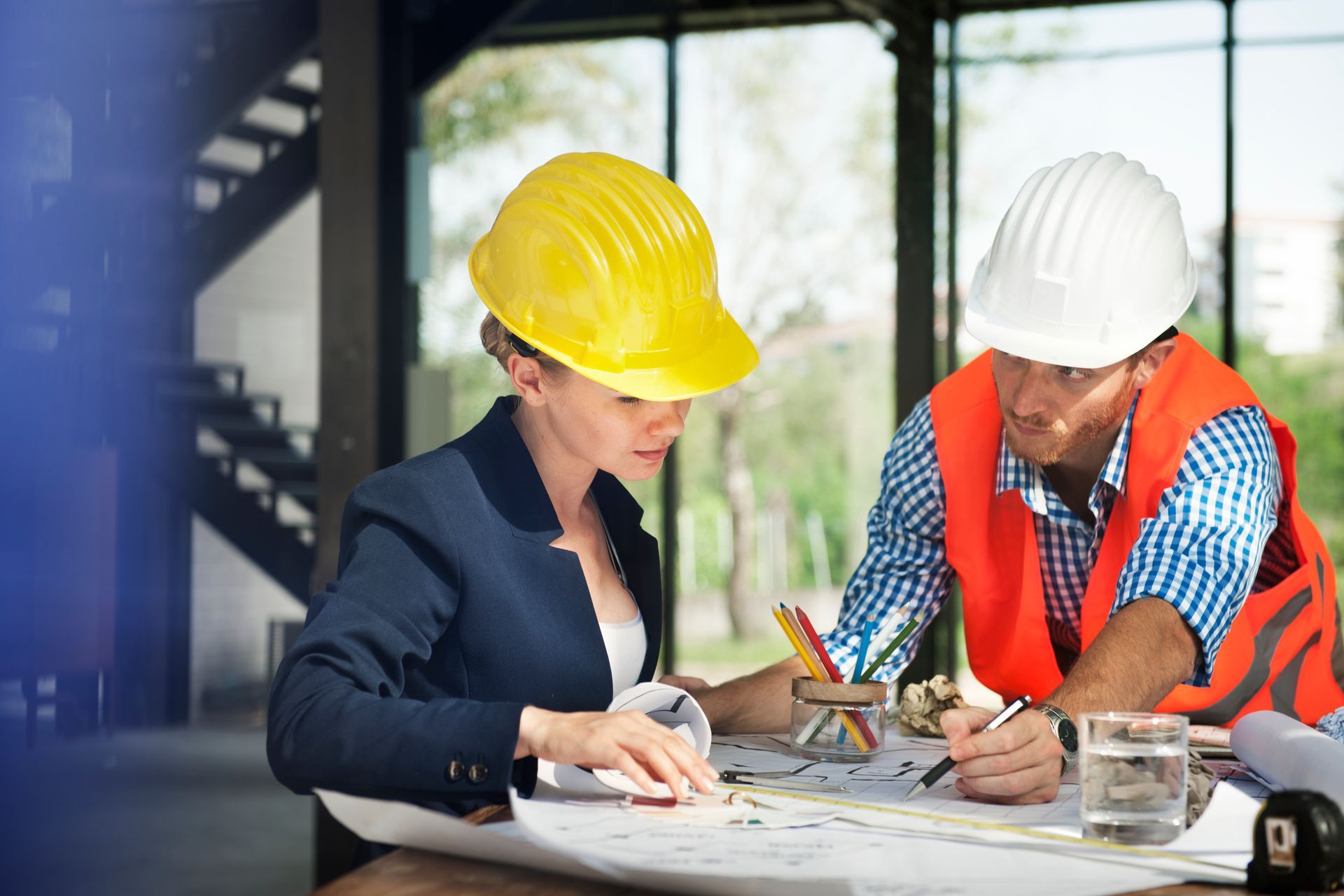 A man and a woman are sitting at a table looking at a blueprint.