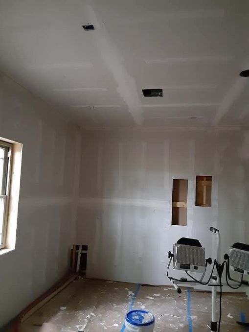 Interior of a room under construction with drywall and exposed electrical boxes.
