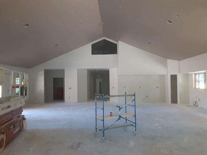 Interior of a room under construction, with high ceilings, unfinished walls, and scaffolding.