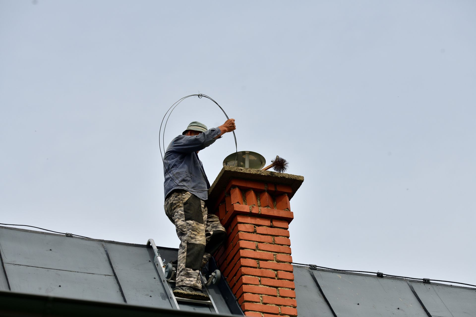 A technician is cleaning a brick chimney from the roof. A technician is cleaning a brick chimney from the roof.