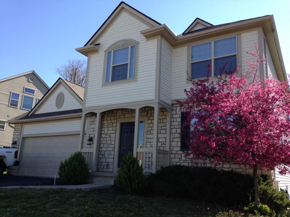 A white house with a pink tree in front of it
