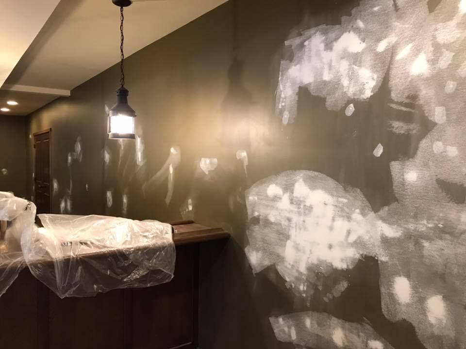 A room with a light hanging from the ceiling and a painting on the wall.