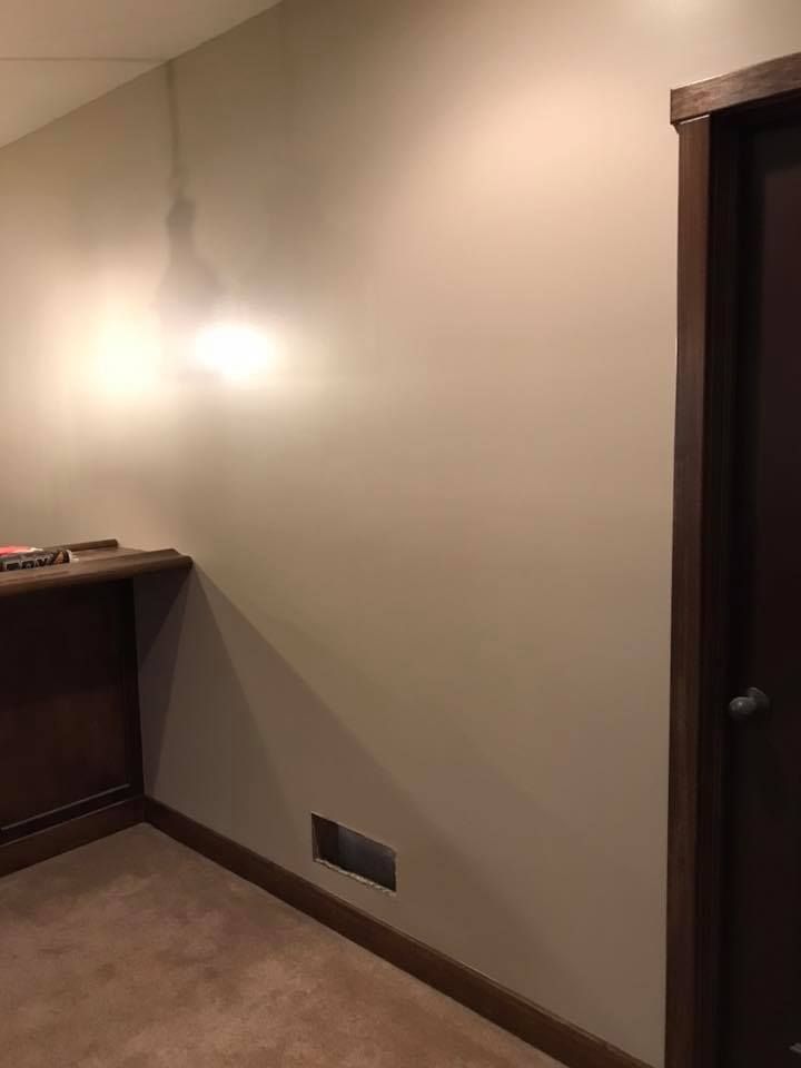 A hallway with a door and a shelf on the wall.